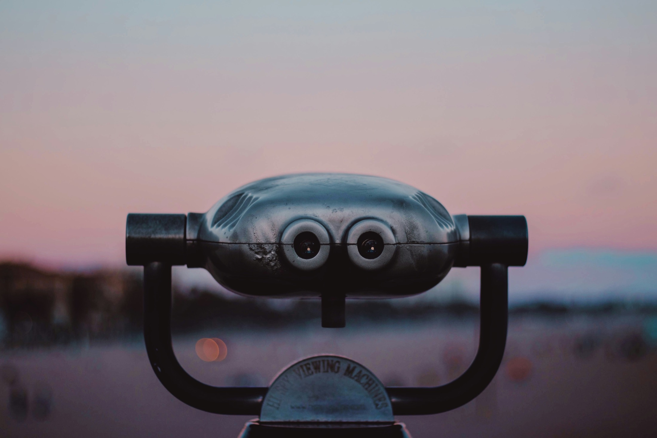 Coin-operated viewing machine facing a soft horizon